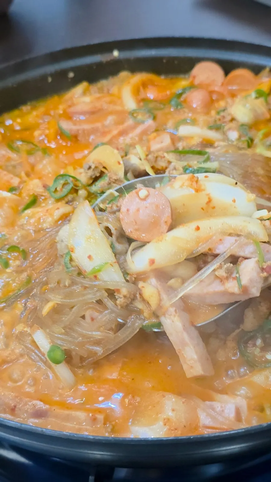 Scooping ingredients out of the budae-jjigae pot