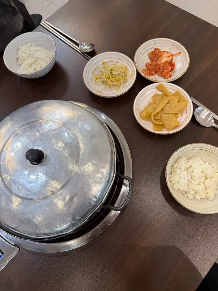 Two servings of Cheongwon budae-jjigae arriving with lids on