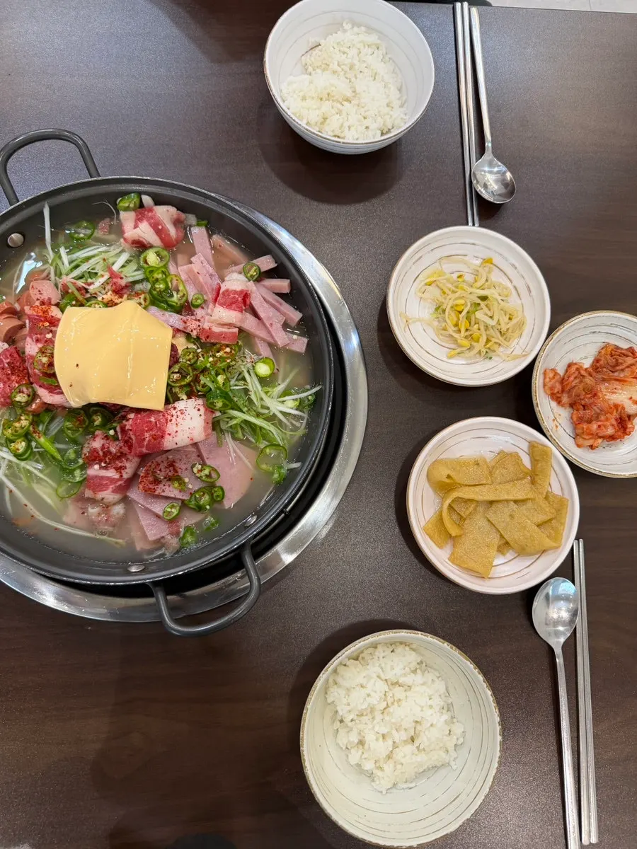 Pot of budae-jjigae with glass noodle and cheese sarie added