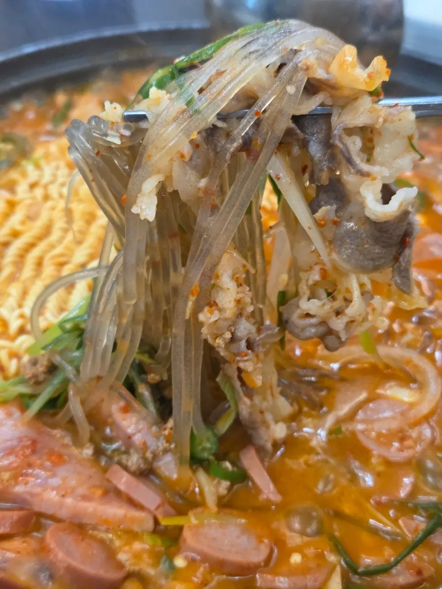 Broth-soaked glass noodles lifted from the pot