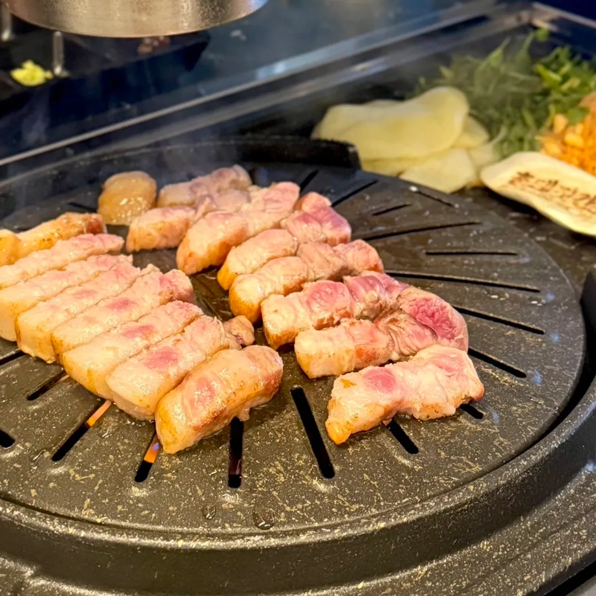 삼겹살에 구운 김치와 미나리를 올린 한 점