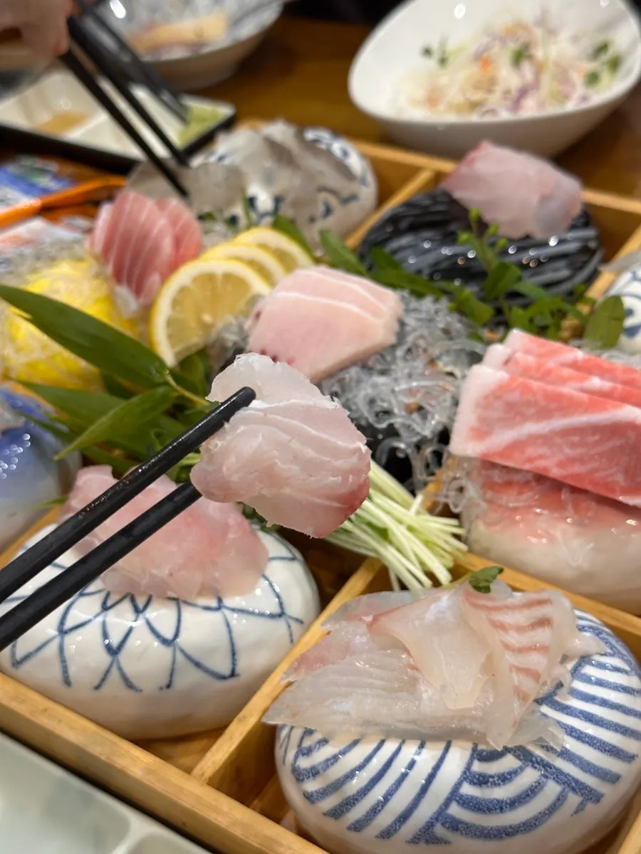A piece of sashimi dipped in soy sauce with wasabi