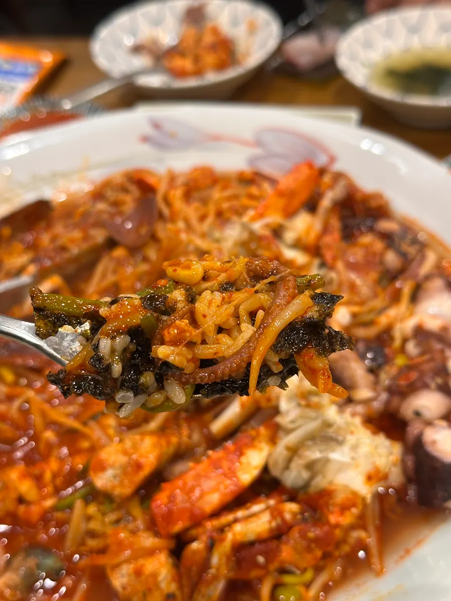 Spicy braised seafood topped with bean sprouts and minari