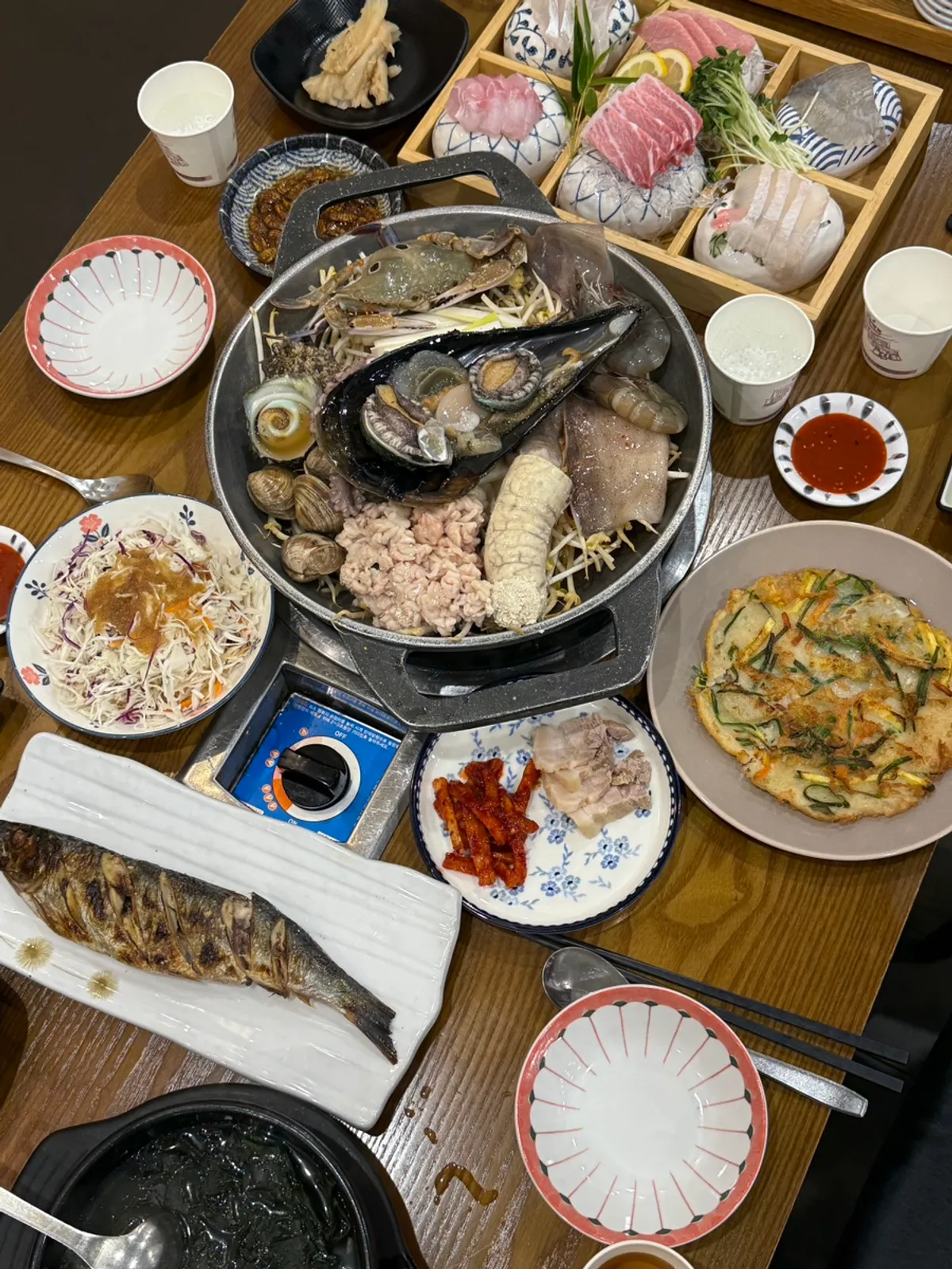 Seafood restaurant meal with assorted sashimi and seafood stew