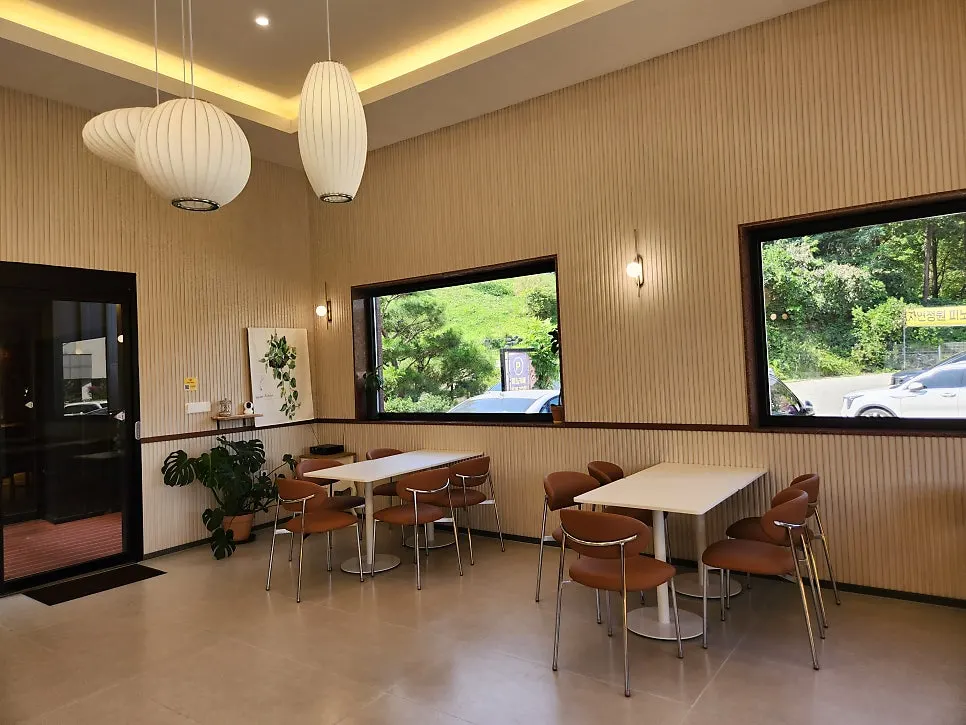 Interior with green plants visible through picture windows