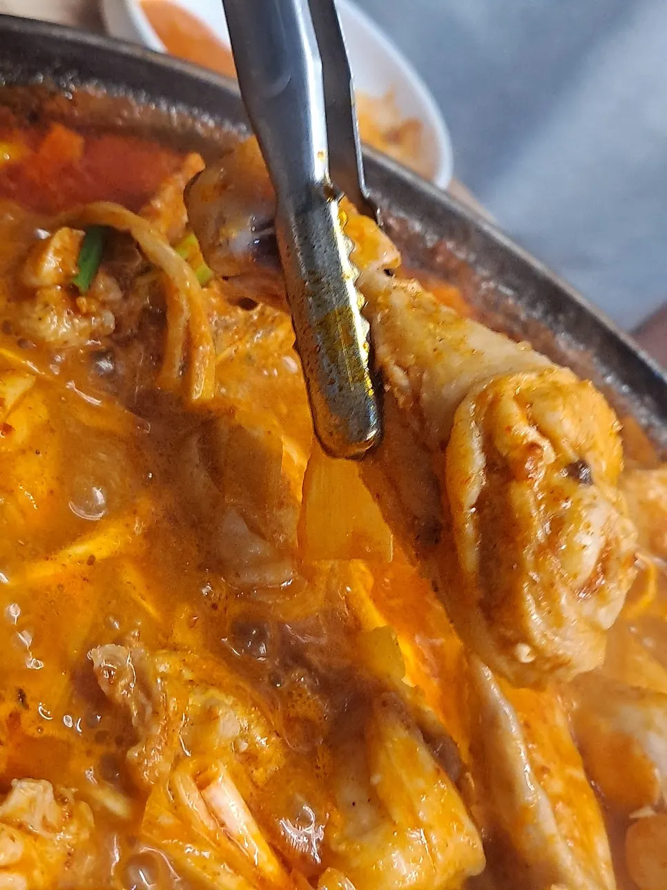 집게로 집어든 큼직한 닭 날개