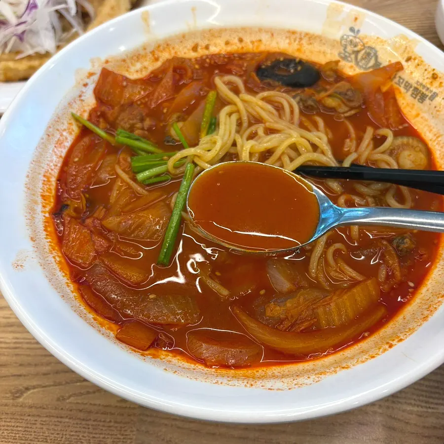 Springy jjamppong noodles lifted up with chopsticks
