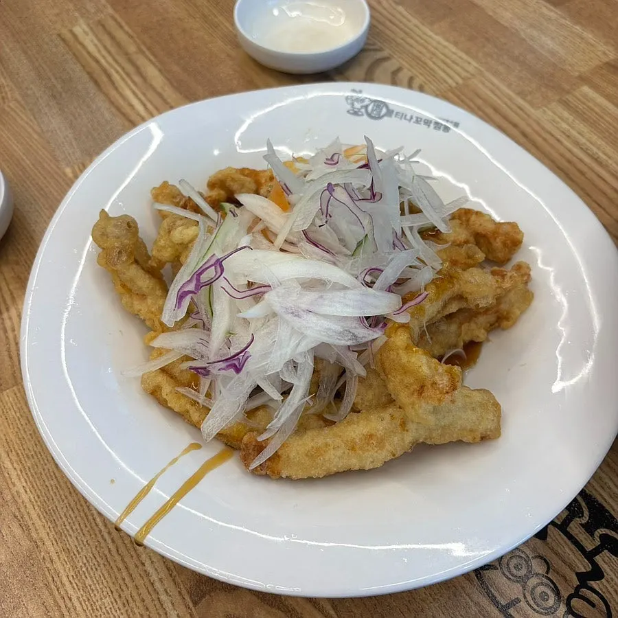 Small sweet and sour pork served with the sauce laid underneath on the plate