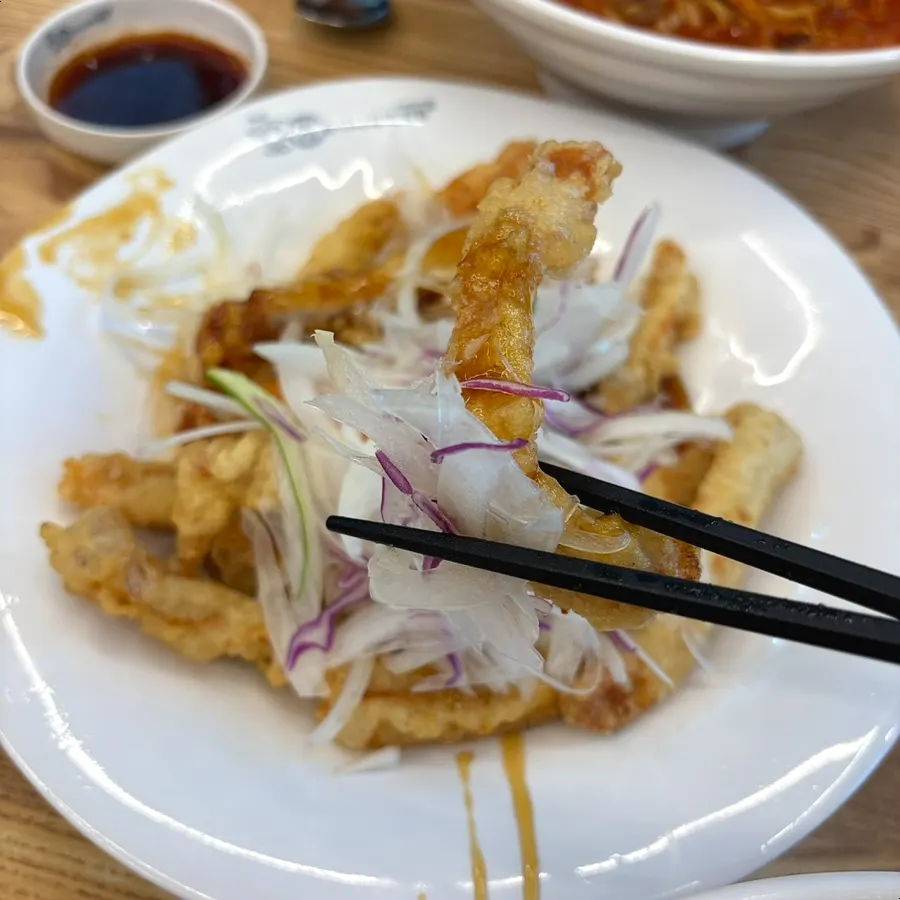 Crispy sweet and sour pork dipped deep into the sauce