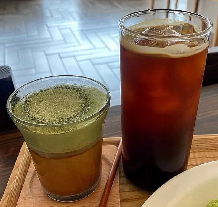 A glass of matcha einspänner topped with matcha cream