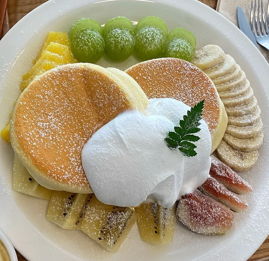 Plate of pancake with pineapple, green grapes, and fig