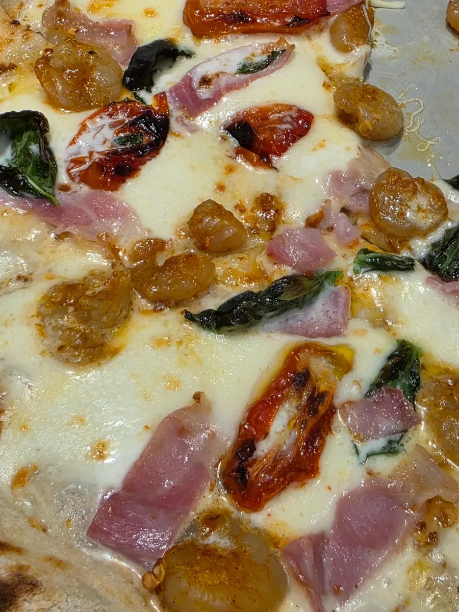 A slice of guanciale pizza being lifted up