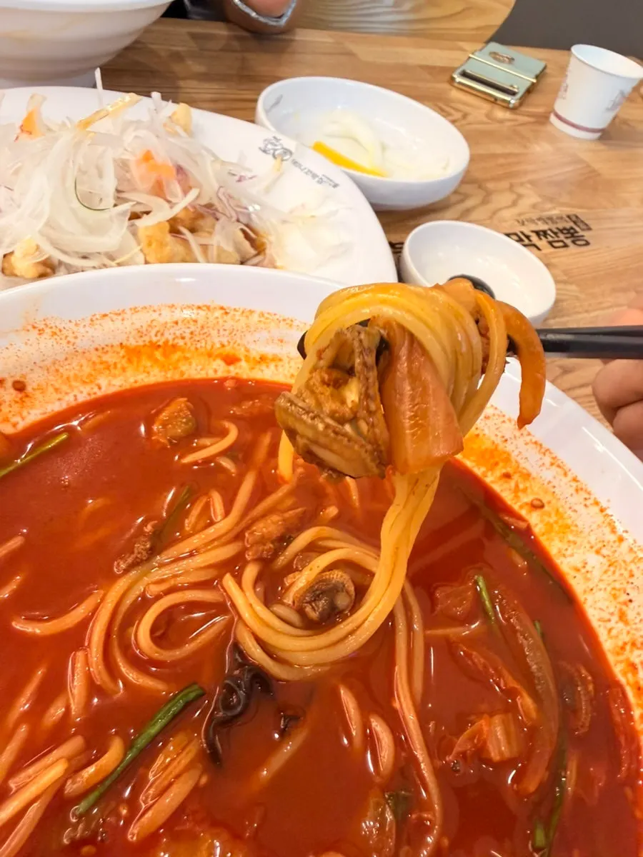 Chopsticks lifting noodles topped with cockles
