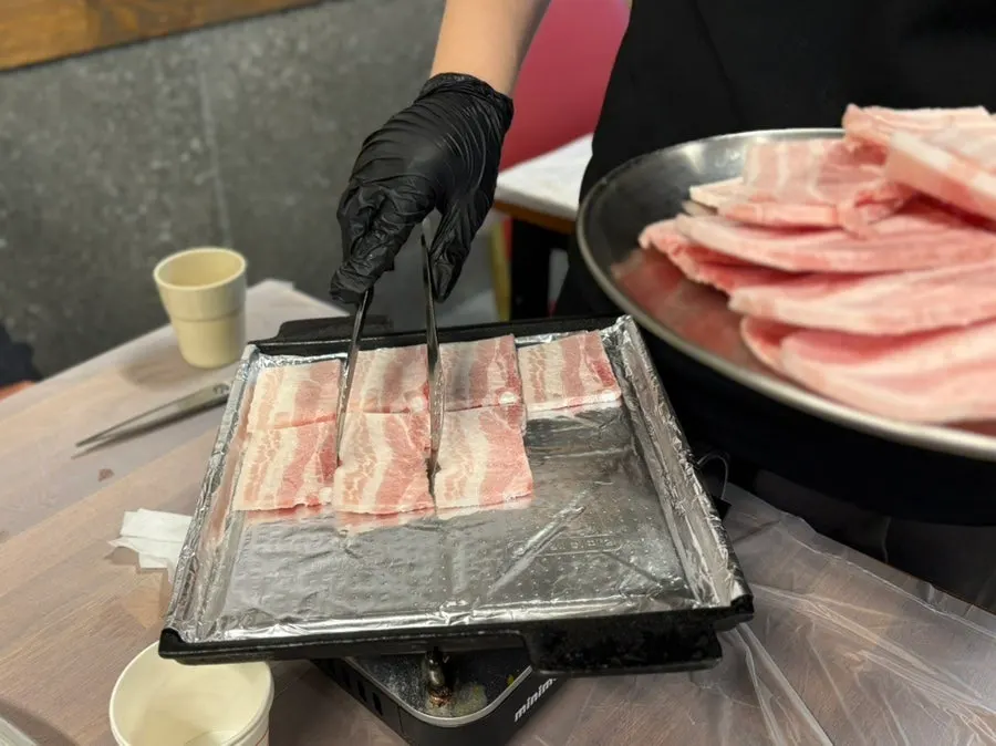Grill with the first batch of meat laid out by staff