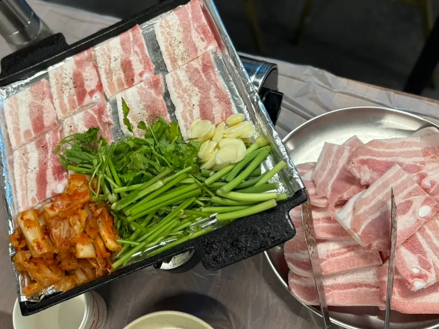 Three servings of frozen pork belly lined up on the grill