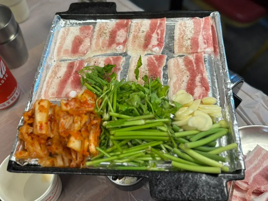 Grill with kimchi and minari cooking alongside the meat