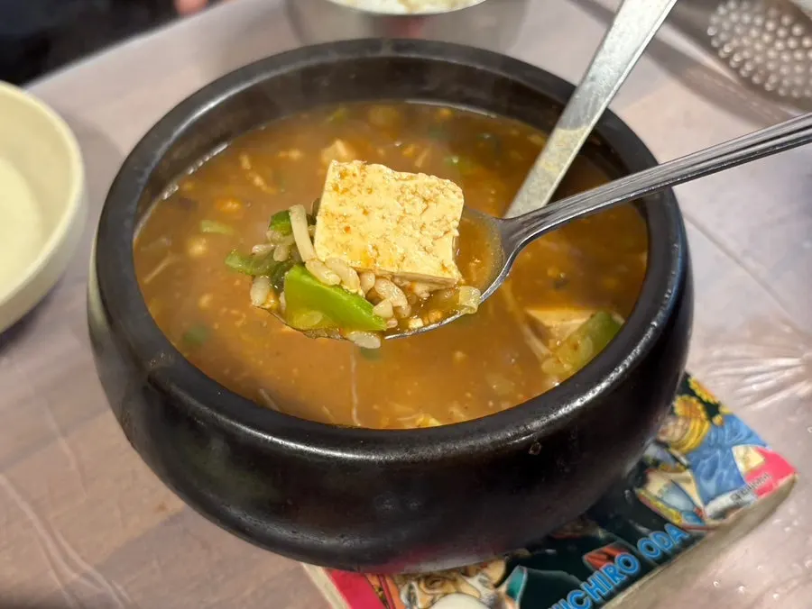 A spoonful of doenjang sulbap lifted from the pot