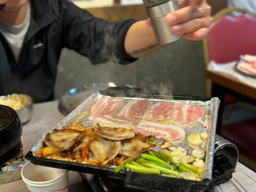 A piece of pork belly topped with wasabi and green onion strips