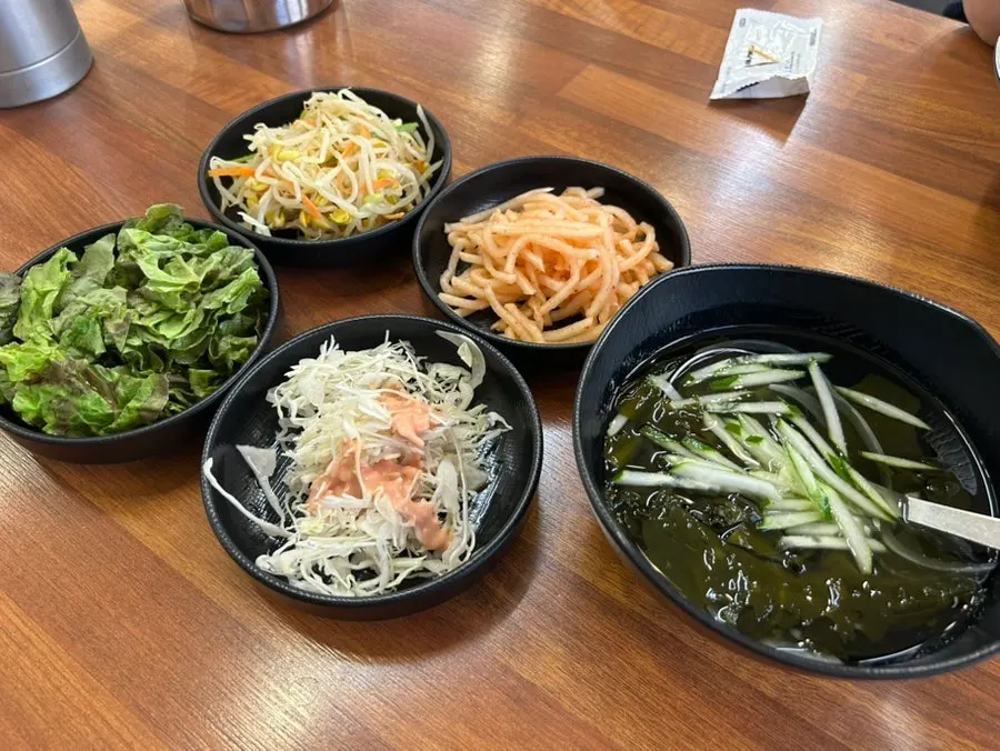 Banchan servidos: lechuga, rábano picante, brotes de soja y ensalada de repollo