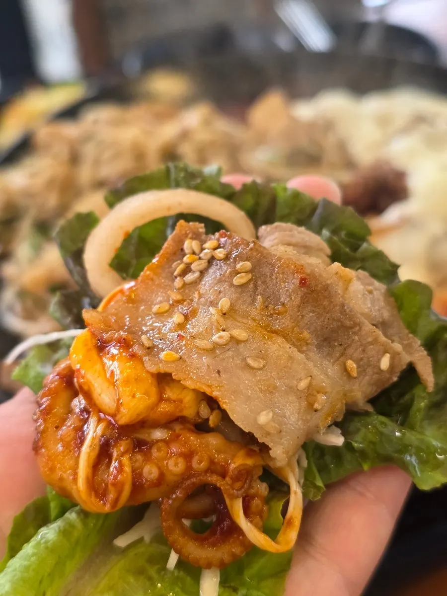 Wrapping jjukkumi and pork belly in a lettuce wrap