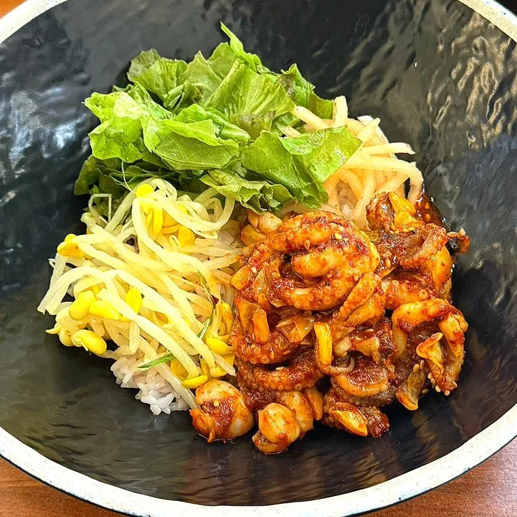 A bite of jjukkumi on plain rice and lettuce