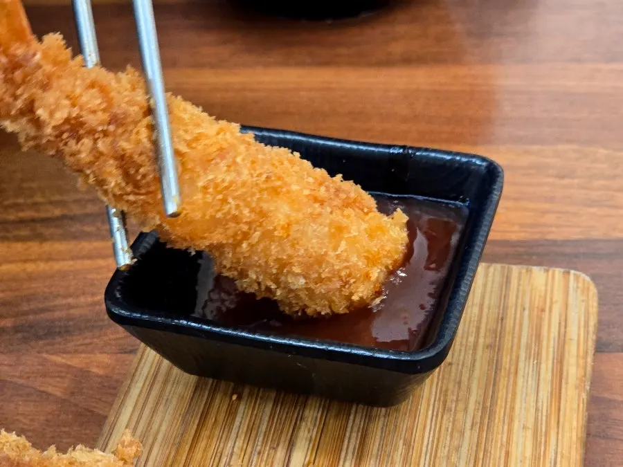 Cross-section of shrimp tempura with chili sauce