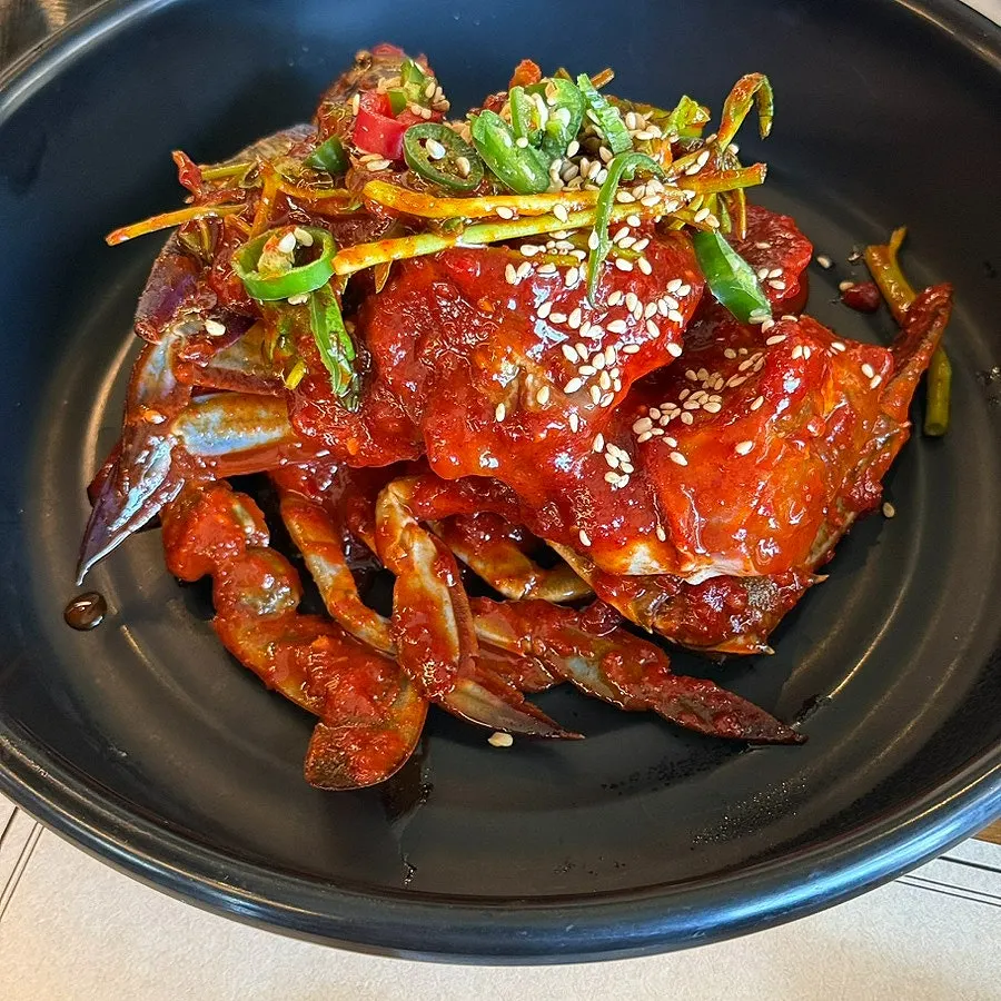 Spicy marinated crab topped with minari and chili peppers