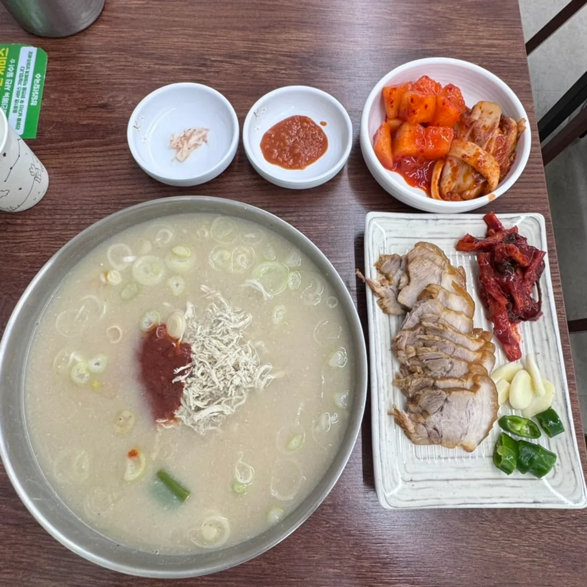 Bowl of spicy chicken kalguksu topped with scallion garnish