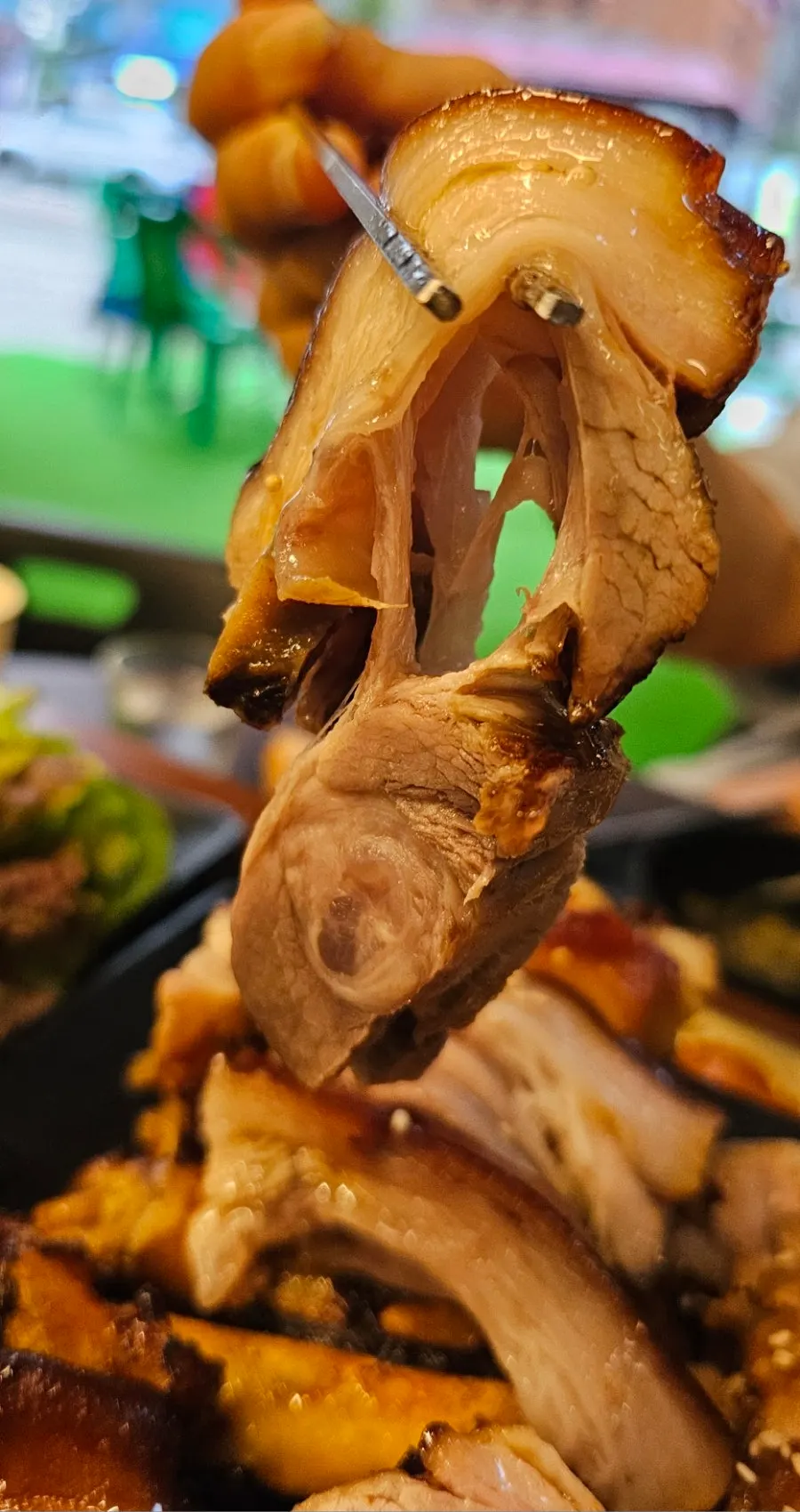 A piece of jokbal lifted with chopsticks