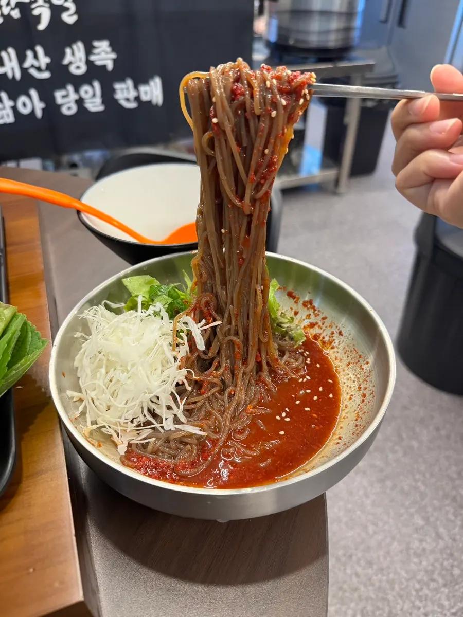 Makguksu noodles rolled up on chopsticks