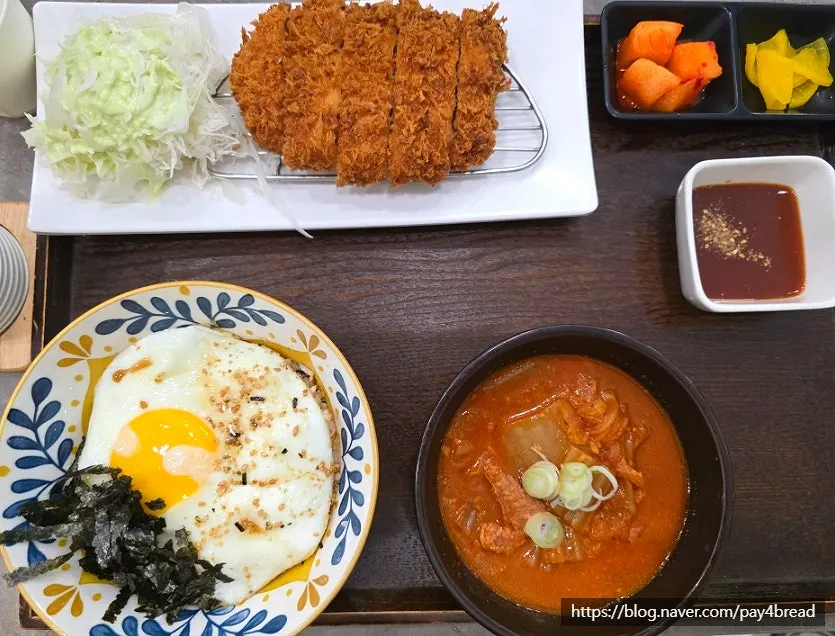 Table setting with pork cutlet, kimchi jjigae, and soy-egg rice