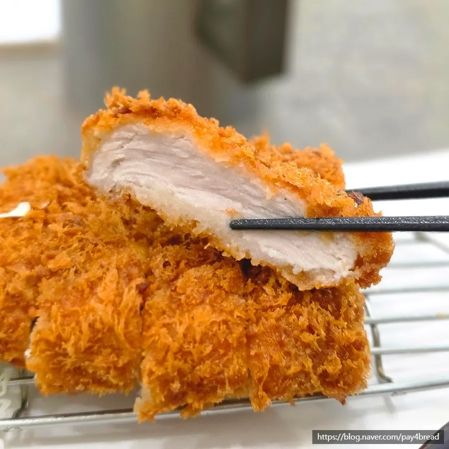 A piece of pork cutlet next to the kimchi jjigae broth