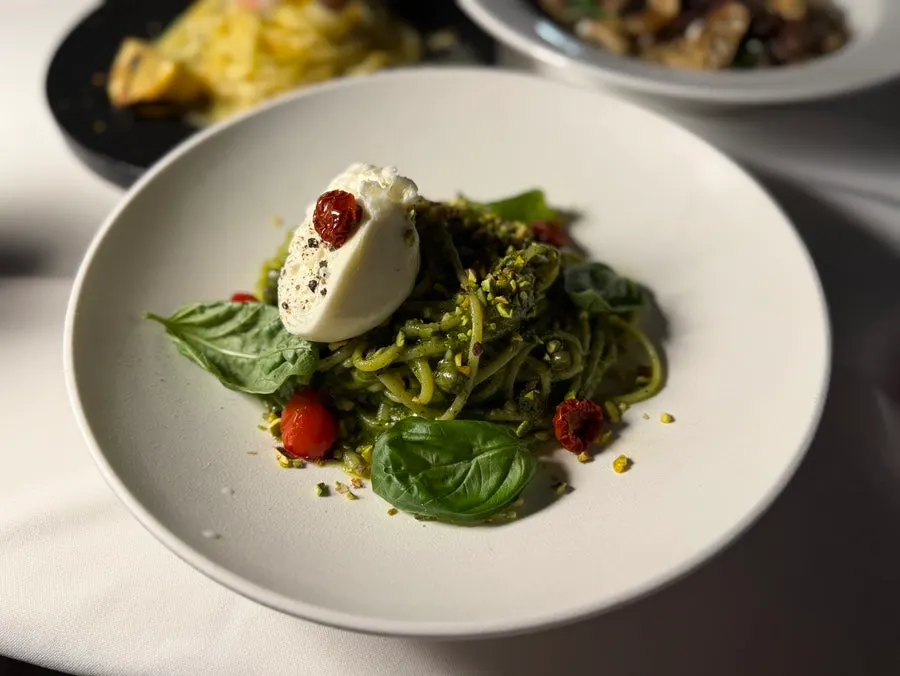 Basil pesto pasta topped with a whole burrata cheese
