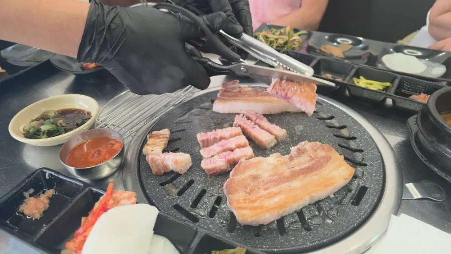 Staff member grilling pork belly on the grill plate