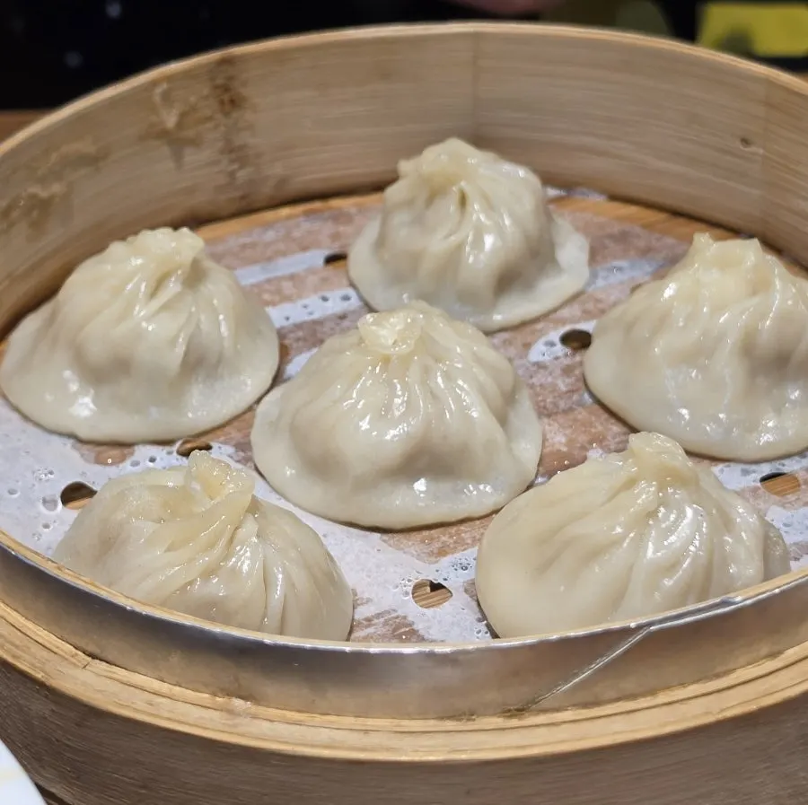 A bite of xiaolongbao showing the broth inside
