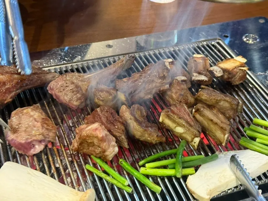 Thick bone-in lamb ribs cooking on the grate