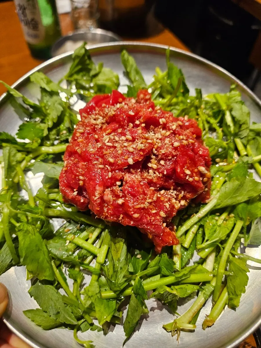 A wrap of minari beef tartare being lifted up