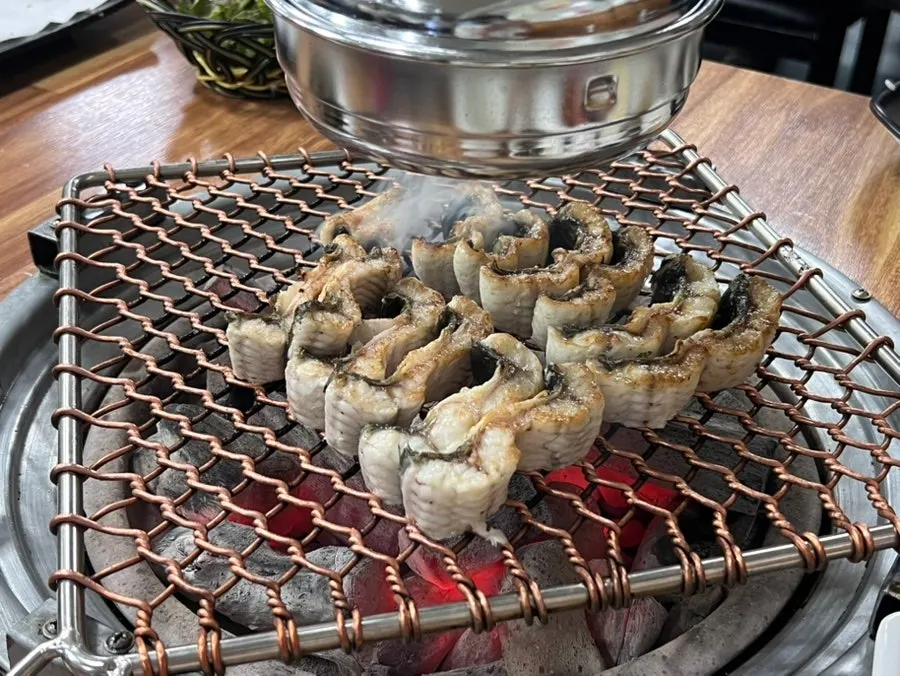 Staff grilling eel over charcoal