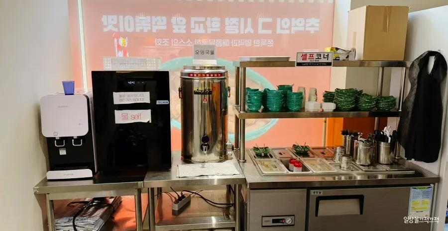Self-service bar with water, fish cake broth, and pickled radish