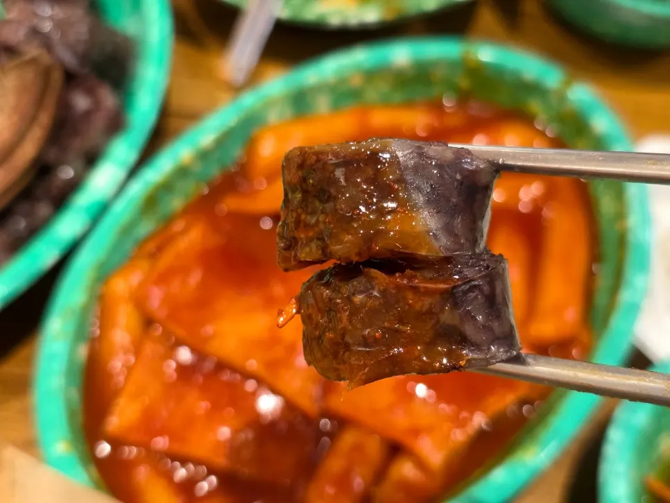 순대를 떡볶이 소스에 찍는 모습