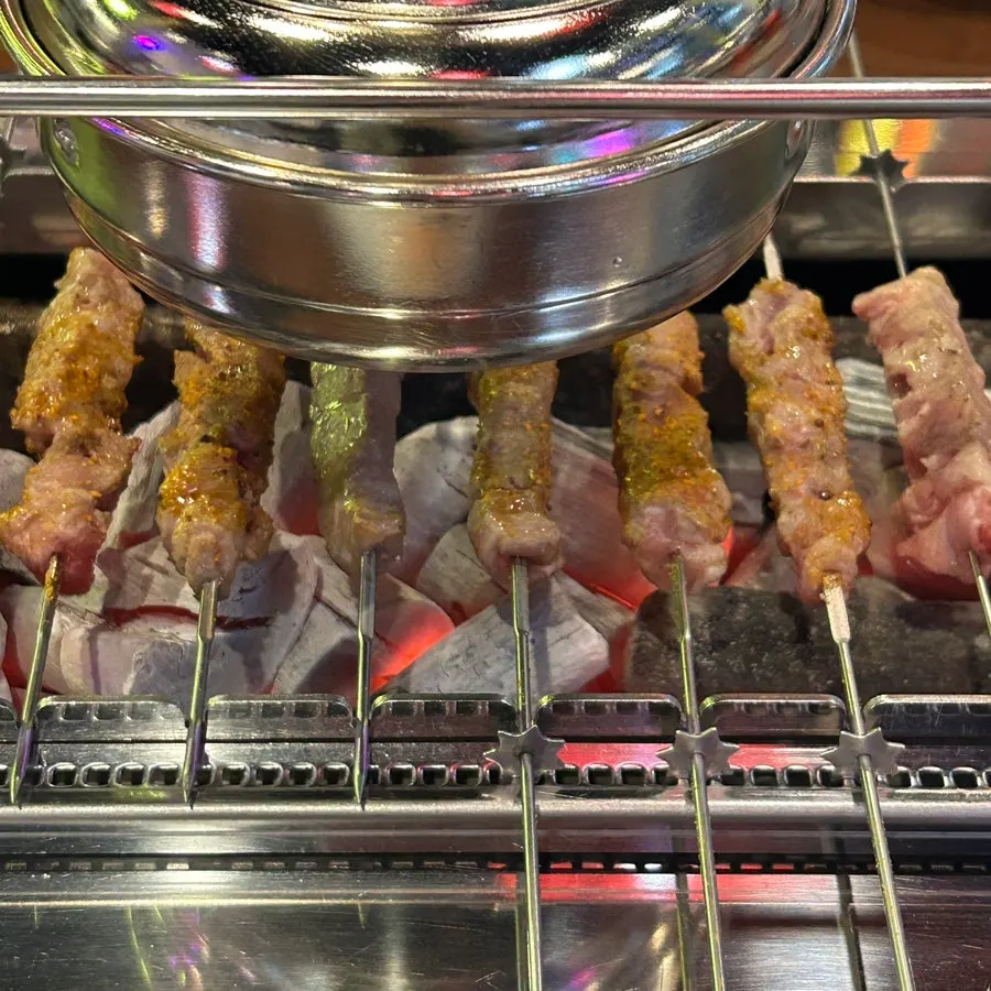 Lamb skewers turning over charcoal on the grill