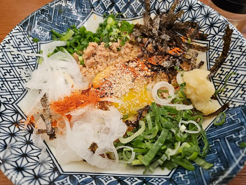 Mazesoba topped with ground meat, green onion, chives, and seaweed