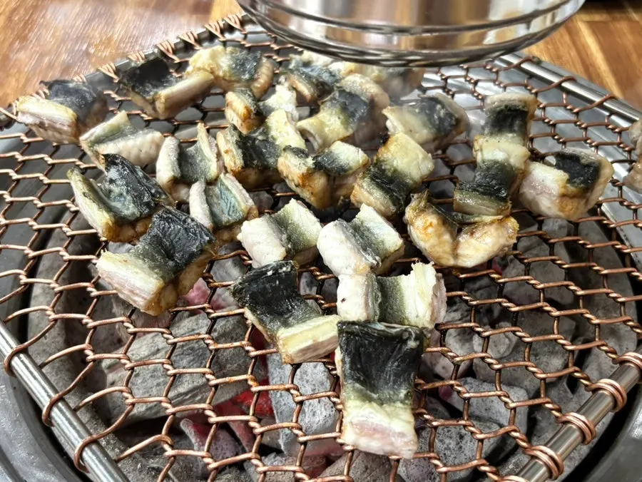 Thick eel meat browning golden on the grill