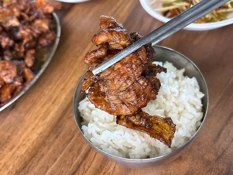 Picking up a piece of gochujang-grilled pork