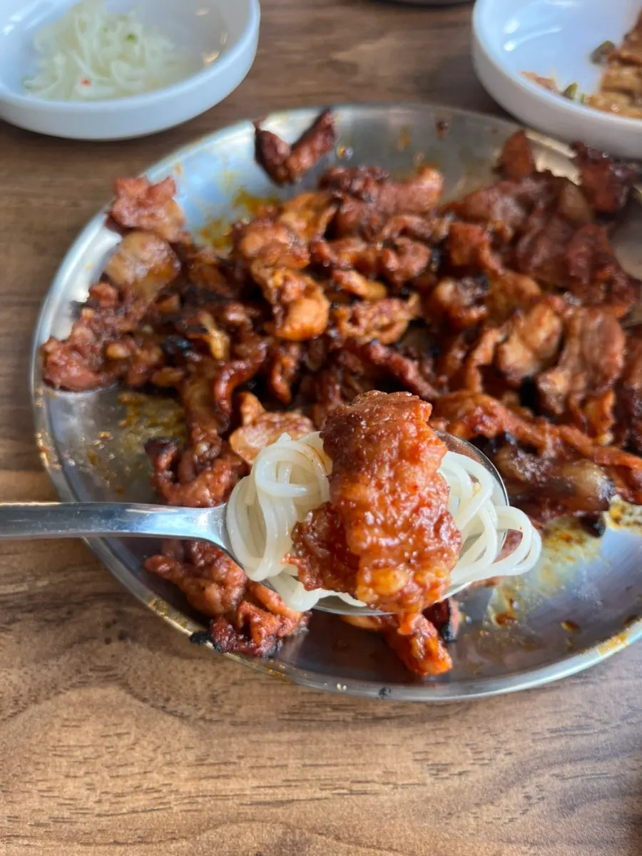 Kimchi-rolled noodles served alongside the meat