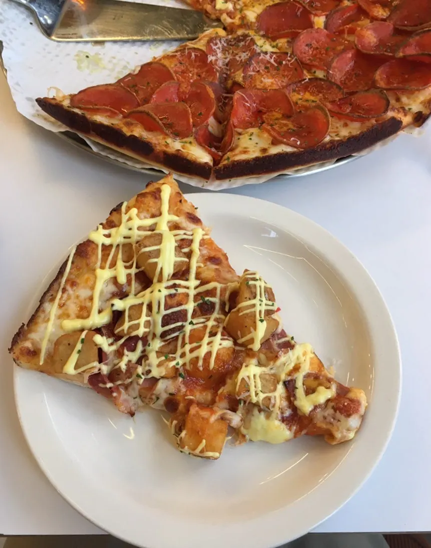 A slice of bacon potato pizza topped with potato and bacon