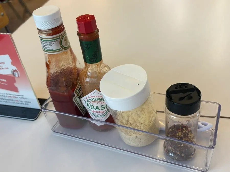 Ketchup, hot sauce, and parmesan cheese on the table
