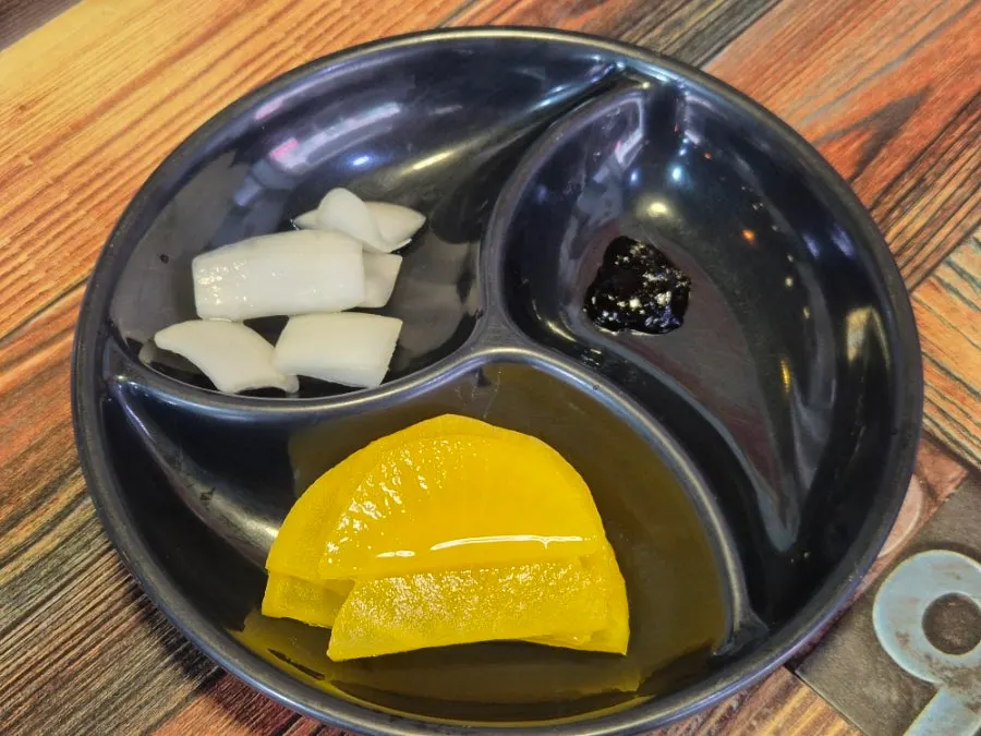 A plate of basic side dishes including crunchy pickled radish