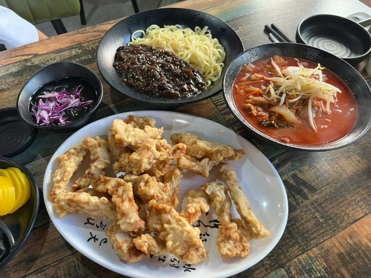 Table spread of jjamppong, jajangmyeon, and glutinous sweet-and-sour pork