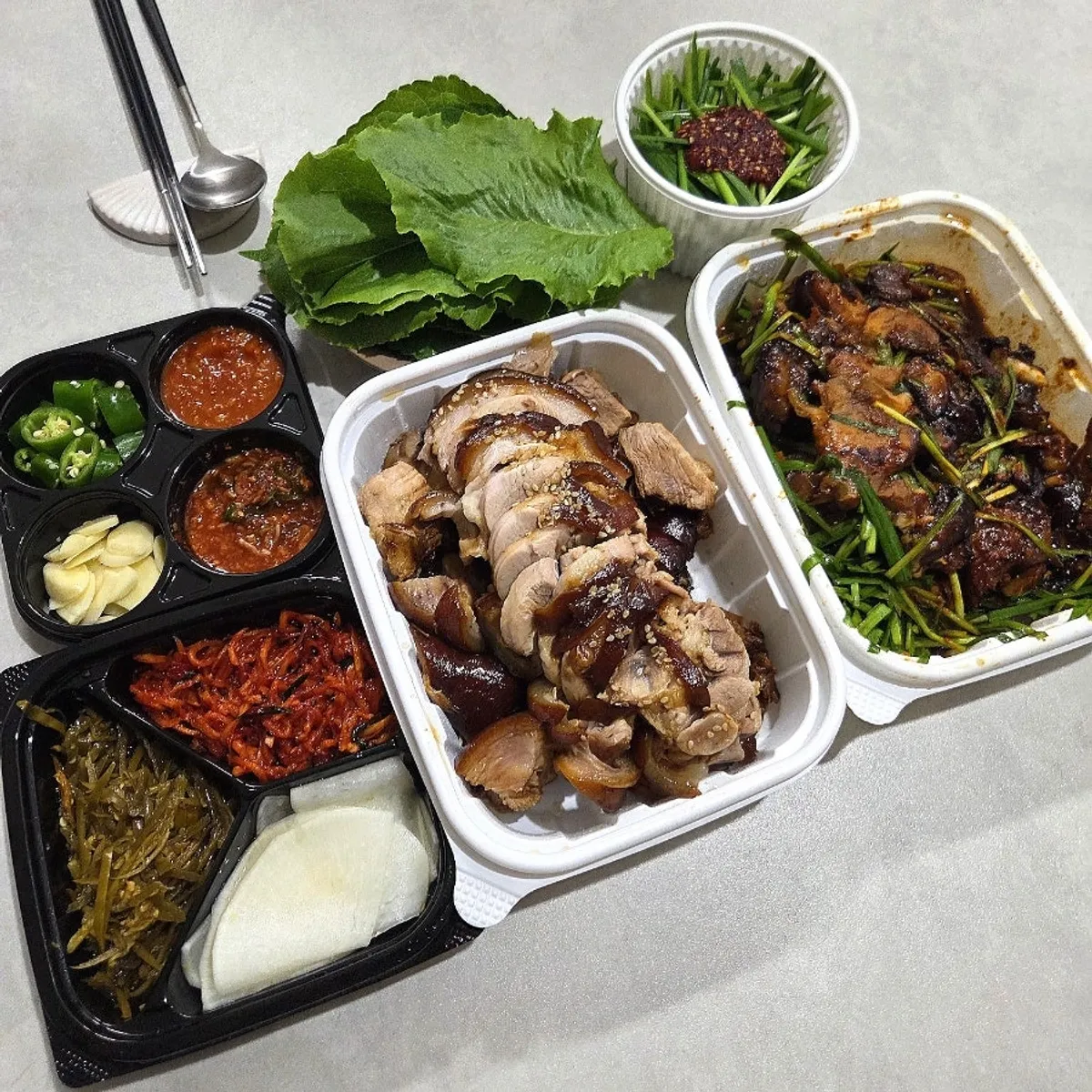 Half-and-half jokbal spread out with lettuce, perilla leaves, and side dishes